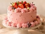 Pink Strawberry Cloud cake topped with fresh strawberries and edible flowers